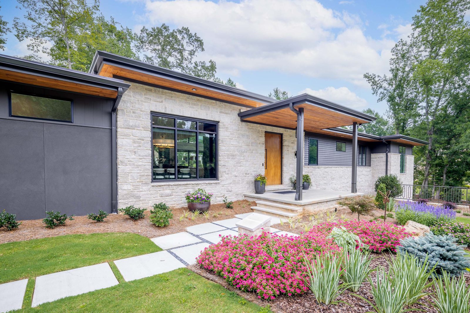 Front elevation with stone, dark stucco and a wood front door — The Ortiz Home, custom home built by Ironwood Construction Group in Sugar Hill, Georgia